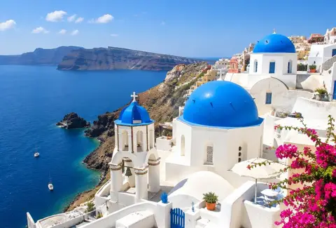 Białe domy i niebieskie kopuły kościołów na Santorini nad morzem